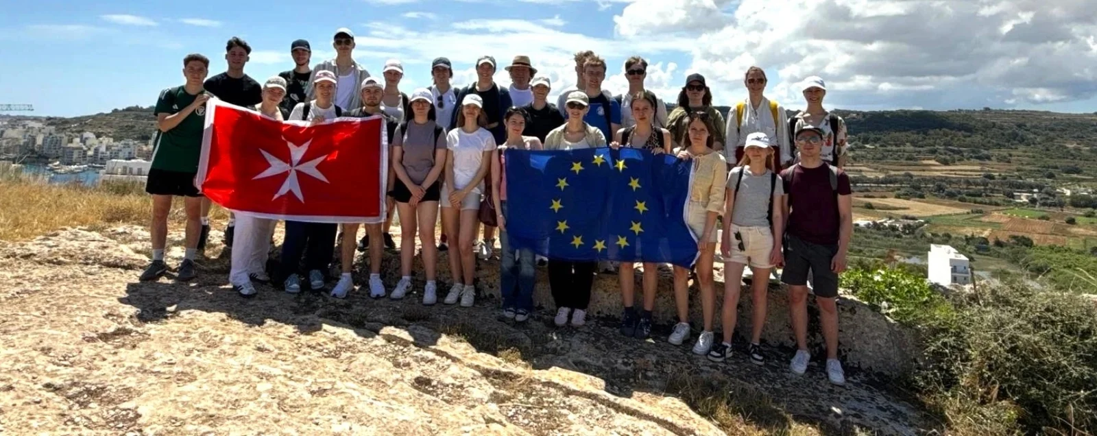 Group photo of the Malta travelers holding a Maltese and European flag