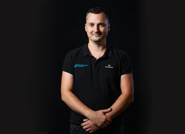 A man in front of a black background smiles at the camera.