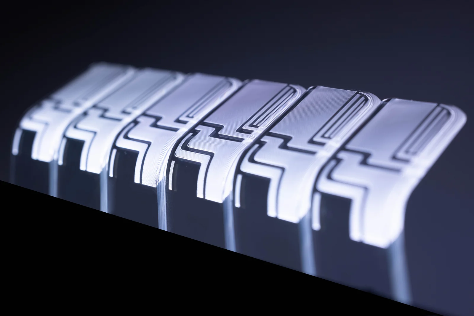 Six white, rectangular objects arranged in a row on a dark background.