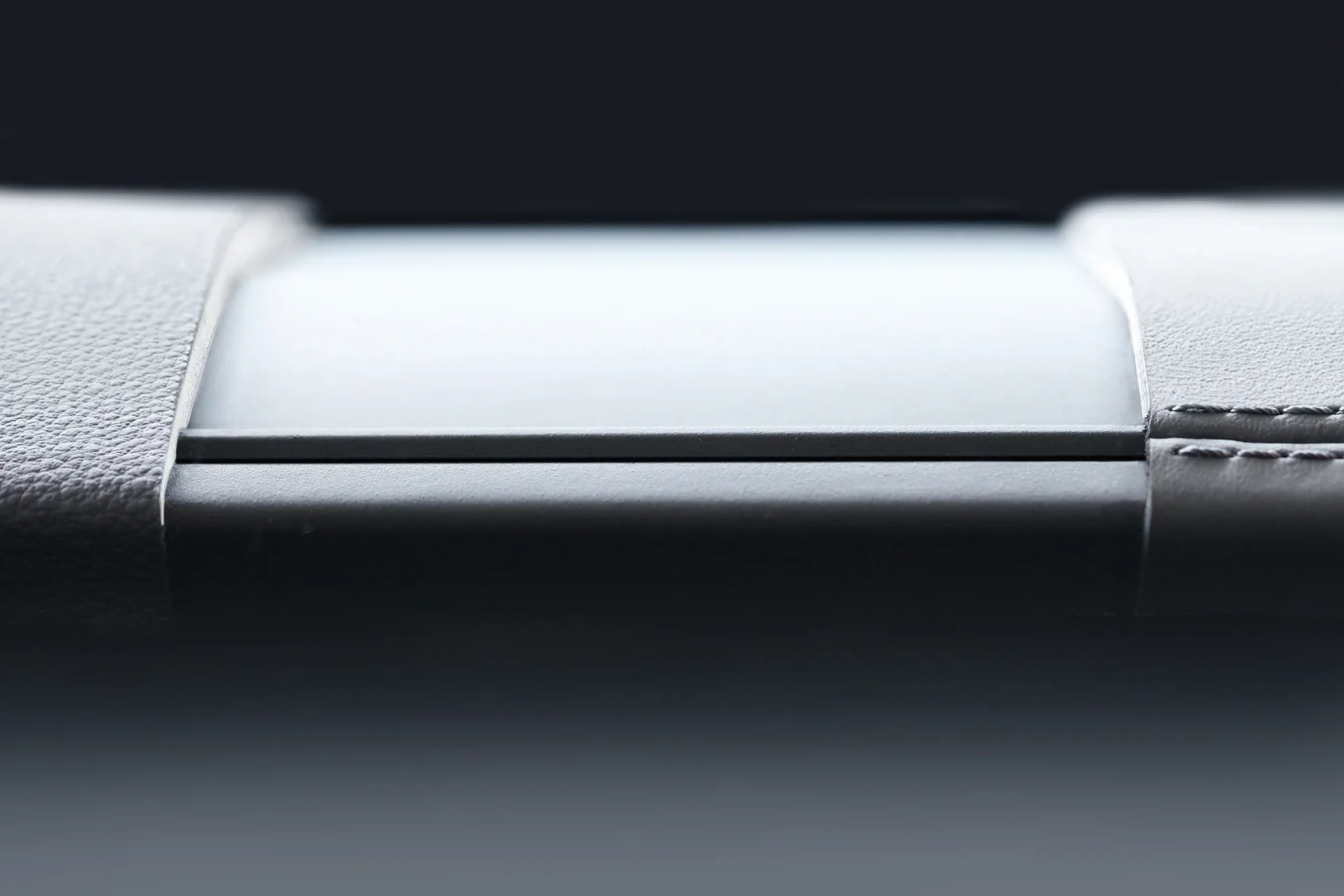 Close-up of a grey surface. On the left and right edges is grey leather that has been worked into the surface.