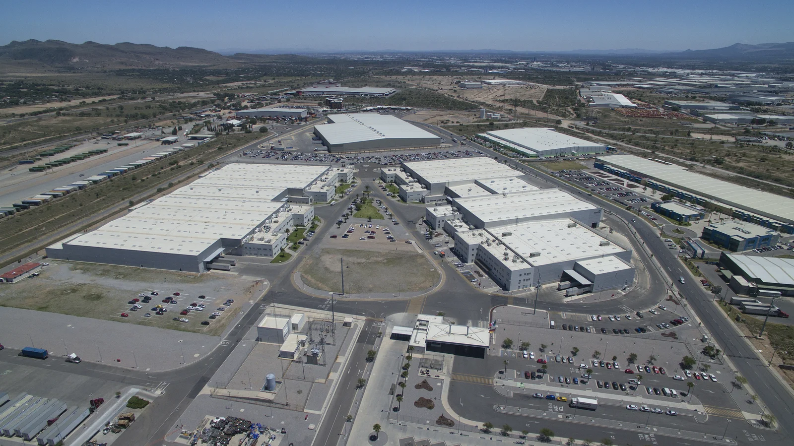 Luftaufnahme eines großen Industriekomplexes mit mehreren weißen Lagerhallen, Straßen und parkenden Autos in San Luis Potosi.