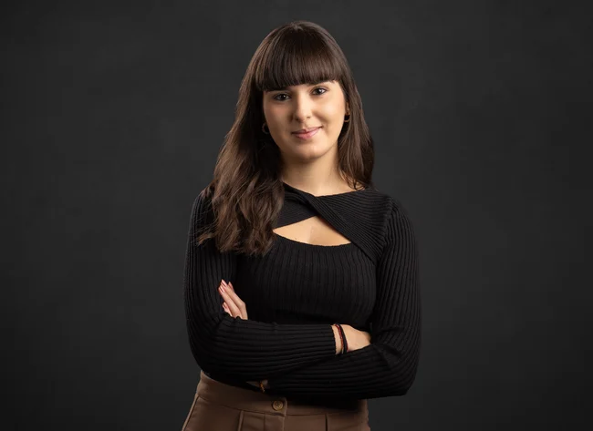 A young woman smiles into the camera with her arms crossed.