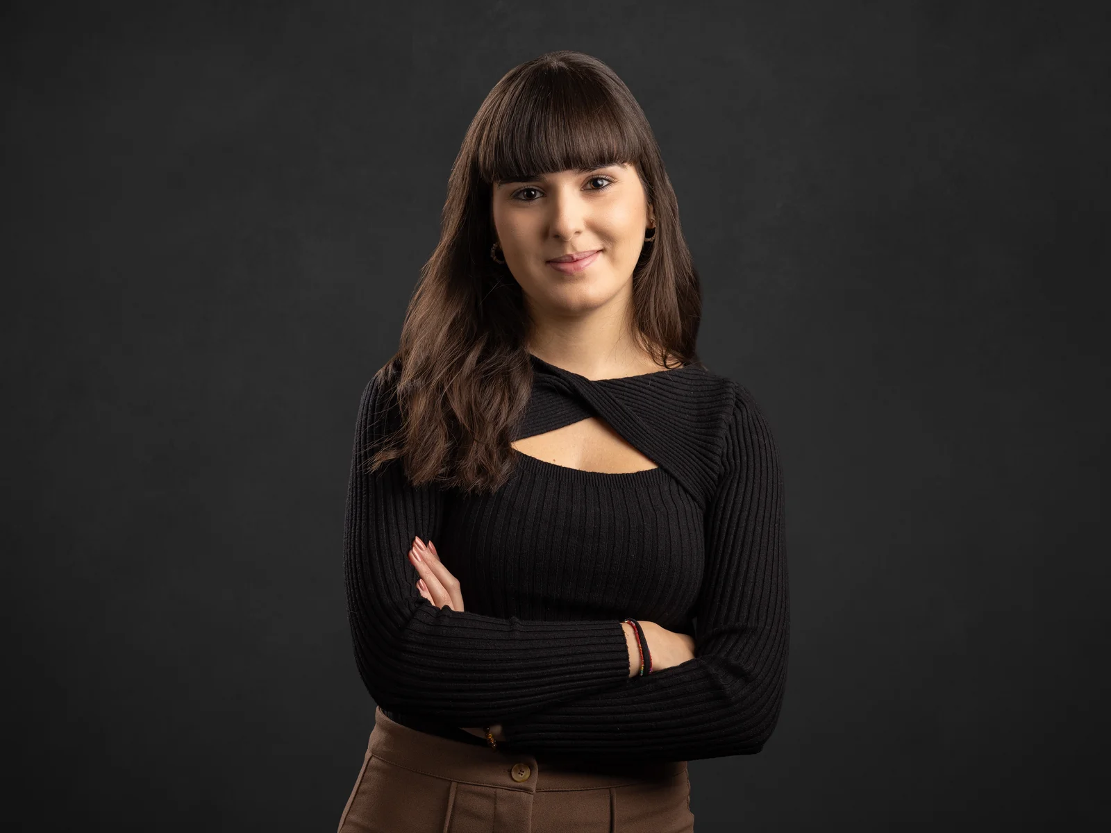 A young woman smiles into the camera with her arms crossed.