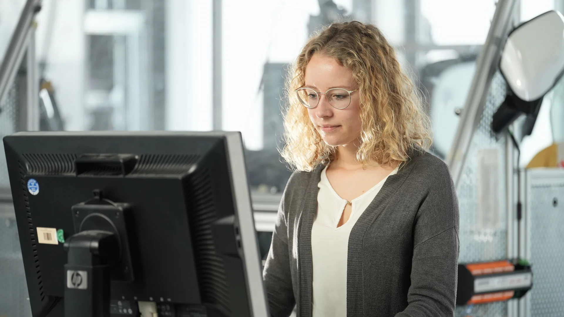 A woman works standing at a computer.