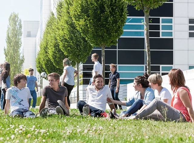 12 trainees on a meadow. 6 of them are playing football, the others are sitting in a circle laughing and chatting.