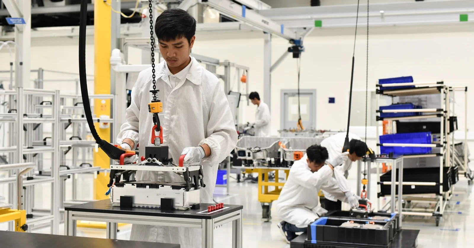 Das Bild zeigt DRÄXLMAIER Produktionsmitarbeiter in der Batteriefertigung in Chonburi. Sie tragen weiße Kittel.  