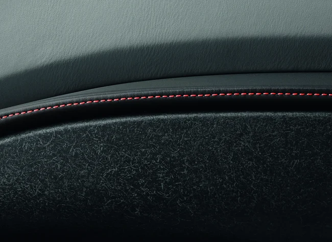 Close-up of the inside of a car door with red stitching. 