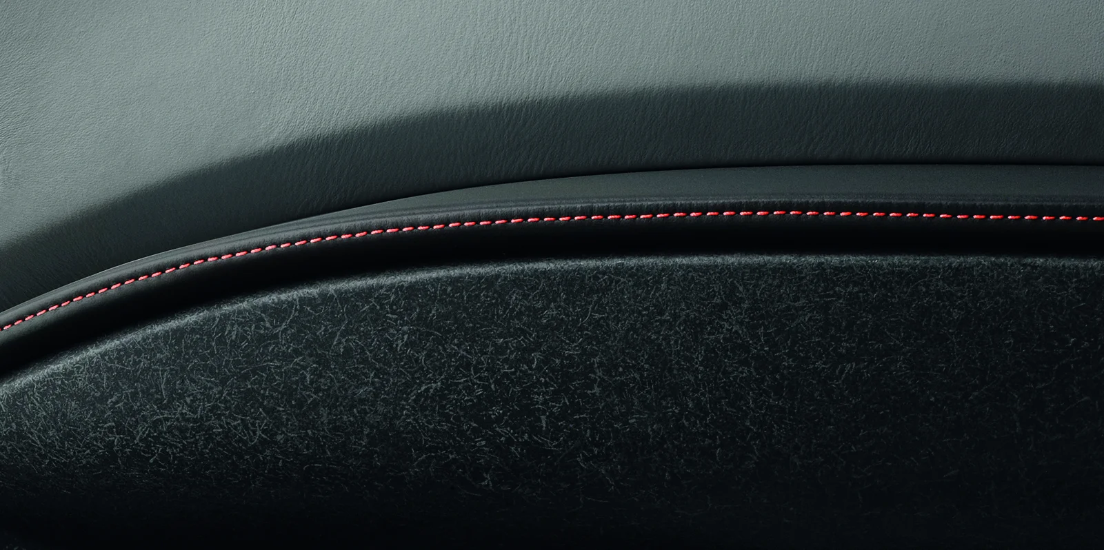 Close-up of the inside of a car door with red stitching. 