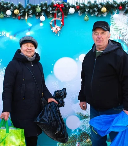 Zwei Personen vor weihnachtlich geschmücktem Hintergrund mit ‚DRÄXLMAIER‘-Schriftzug.