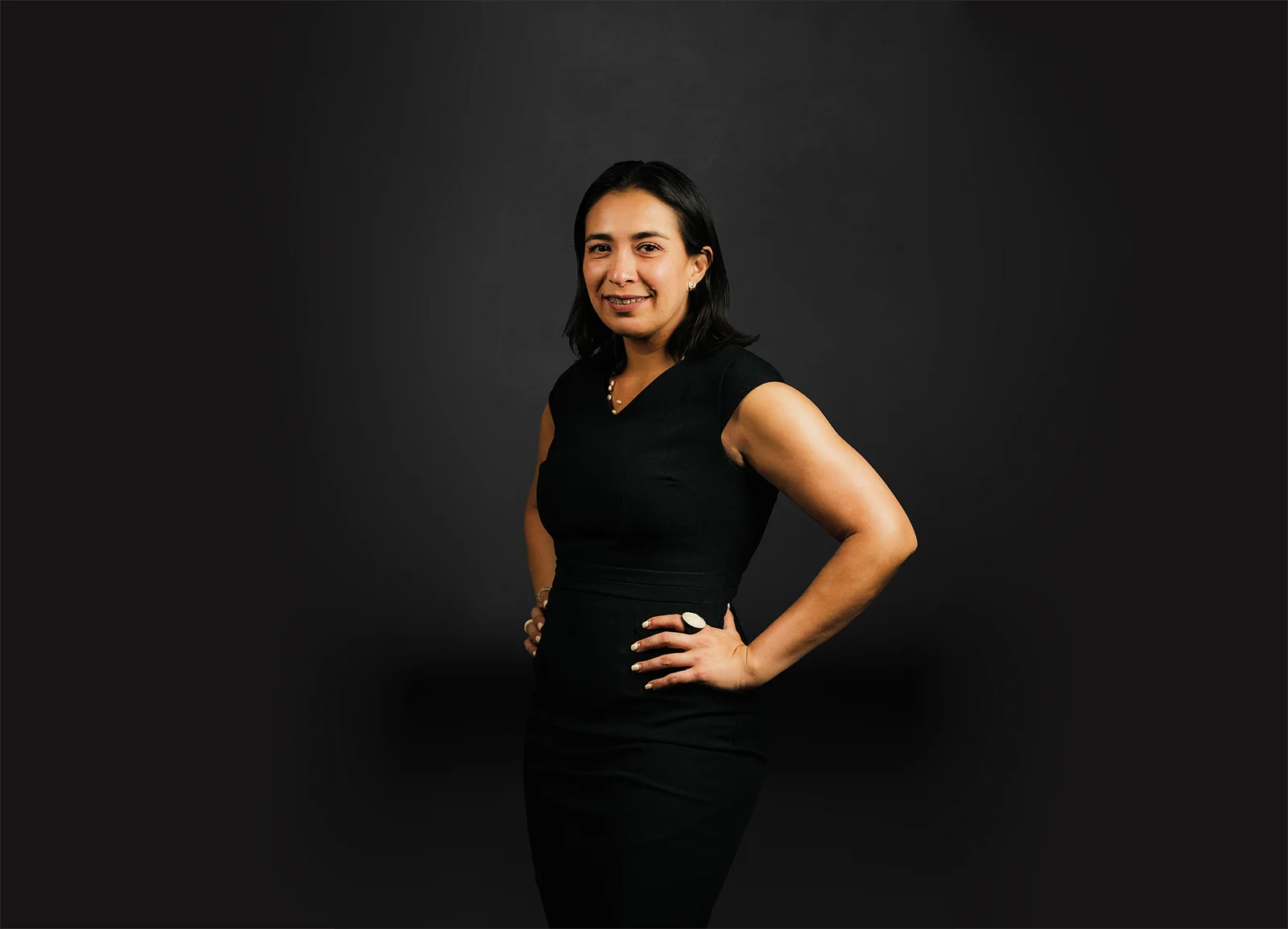 A woman in front of a black background smiles at the camera.