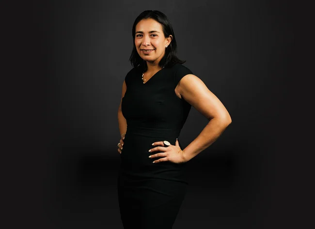 A woman in front of a black background smiles at the camera.