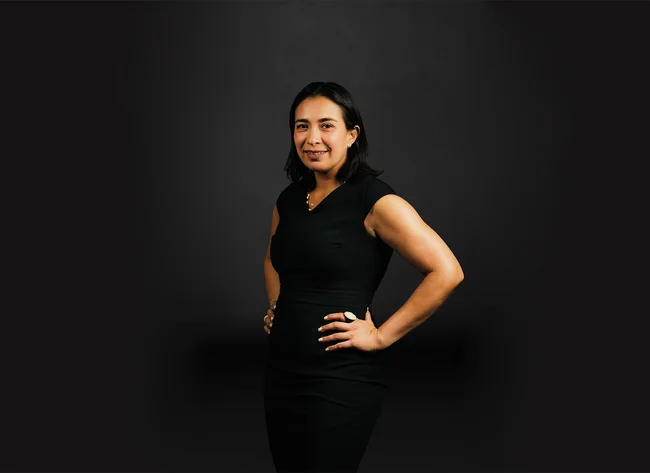 A woman in front of a black background smiles at the camera.