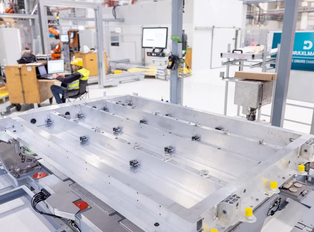Eine Industriehalle der Firma DRÄXLMAIER. Arbeiter und Maschinen sind auf dem Bild.