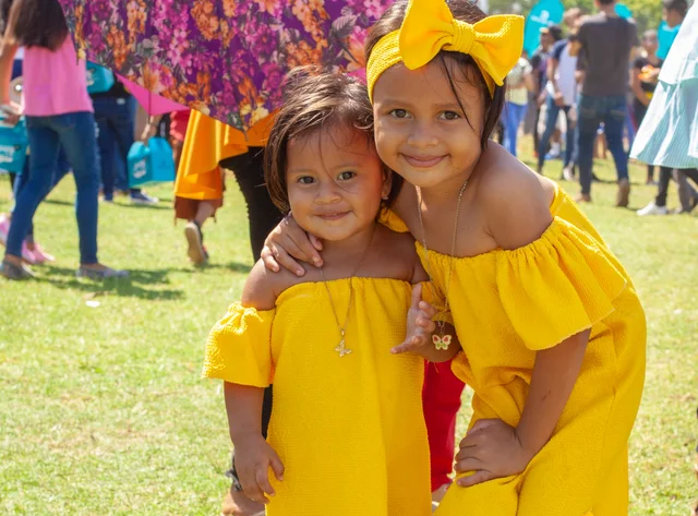 Two young girls in yellow dresses on a meadow at a family event in Nicaragua.
