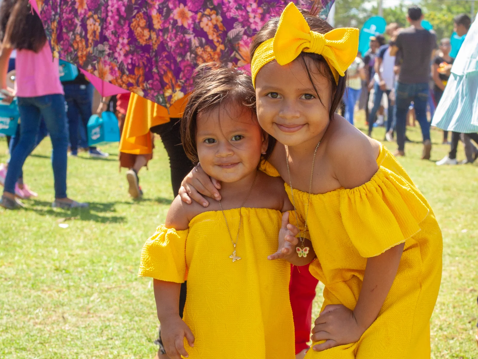 Zwei junge Mädchen in gelben Kleidern auf einer Wiese beim Familienevent in Nicaragua.