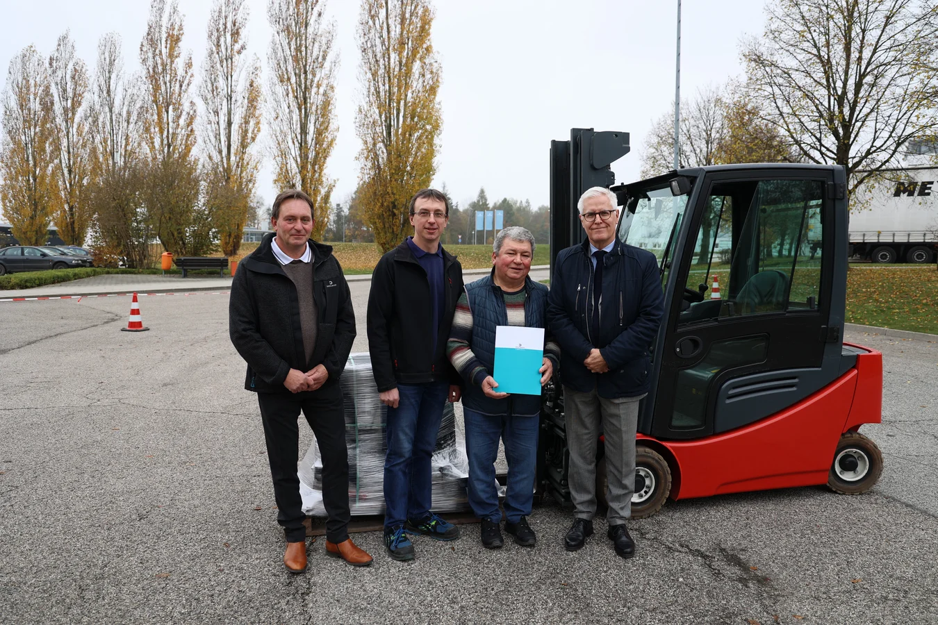 Vor dem gestifteten Gabelstapler stehen (von links nach rechts) Bartholomäus Mühlhofer aus der DRÄXLMAIER Logistik, Johann Voglmeier, 2. Vorstand, Vorstand a.D. Dionys Irlbeck sowie Olivier Dubois, verantwortlich für Marketing und Kommunikation. 