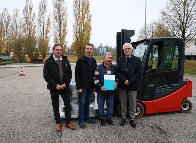 Vor dem gestifteten Gabelstapler stehen (von links nach rechts) Bartholomäus Mühlhofer aus der DRÄXLMAIER Logistik, Johann Voglmeier, 2. Vorstand, Vorstand a.D. Dionys Irlbeck sowie Olivier Dubois, verantwortlich für Marketing und Kommunikation. 