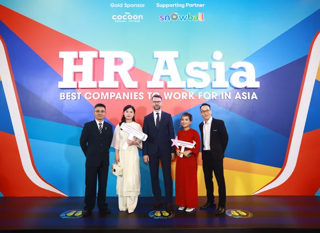 5 people stand smiling in front of a colorful background. An award is presented for the best employers in Asia. 