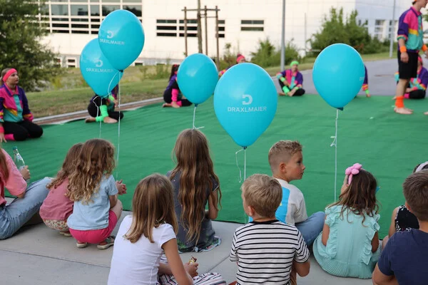 Kinder mit blauen Luftballons beim Zuschauen der Showtanzgruppe
