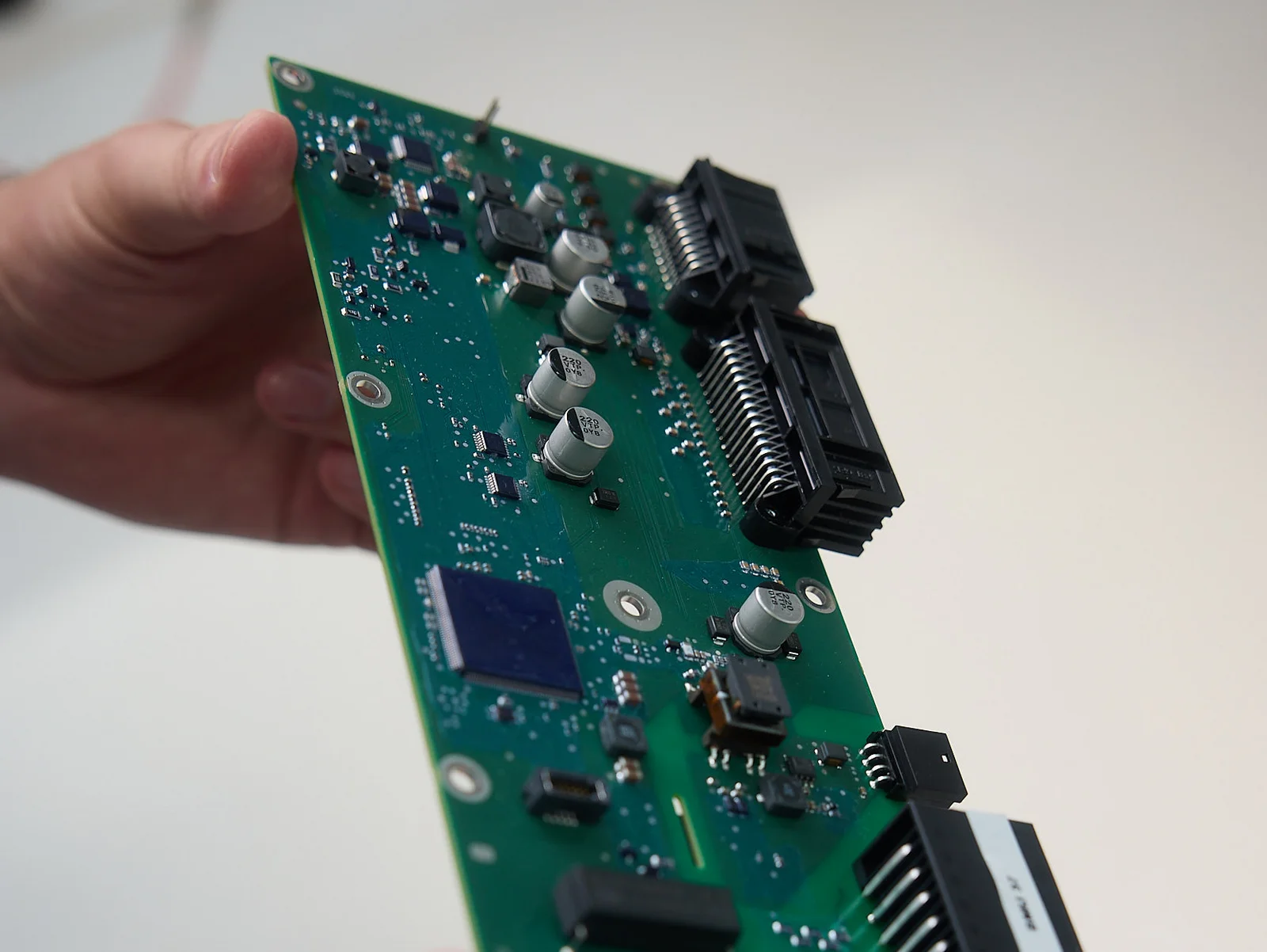 Eine Person hält eine grüne Leiterplatte mit verschiedenen elektronischen Bauteilen.