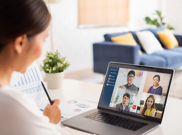 A woman is sitting at a desk. She is in an online meeting. 