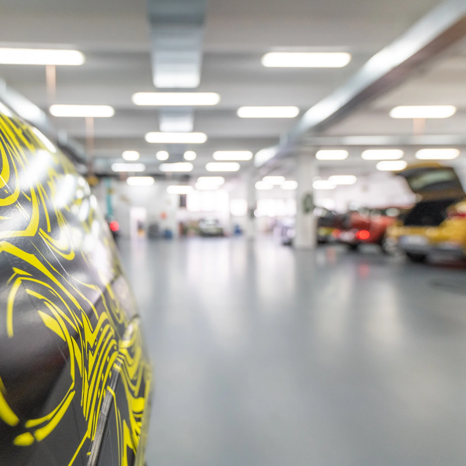Interior view of a well-lit DRÄXLMAIER garage with several cars.