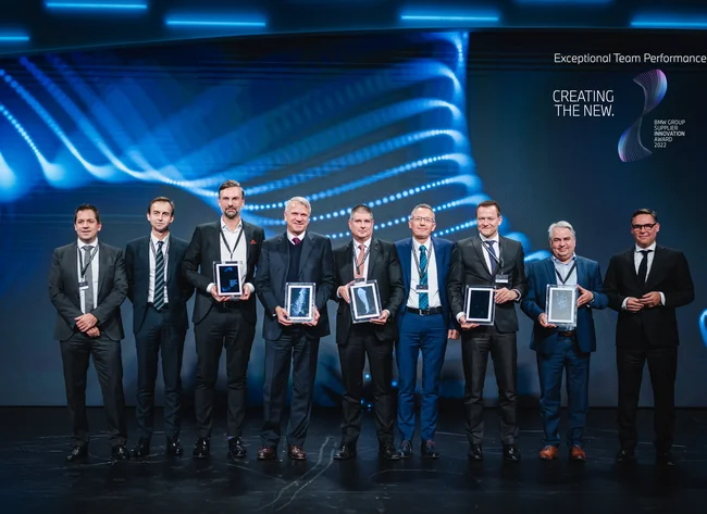 Nine men smile into the camera. The BMW Supplier Award is presented. 