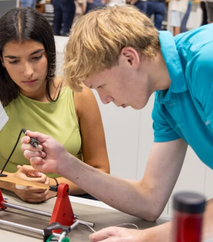 Trainee shows visitor how to solder