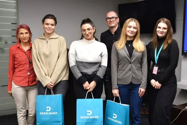 Sechs Personen in einer Reihe, drei halten blaue Taschen mit weißem Aufdruck