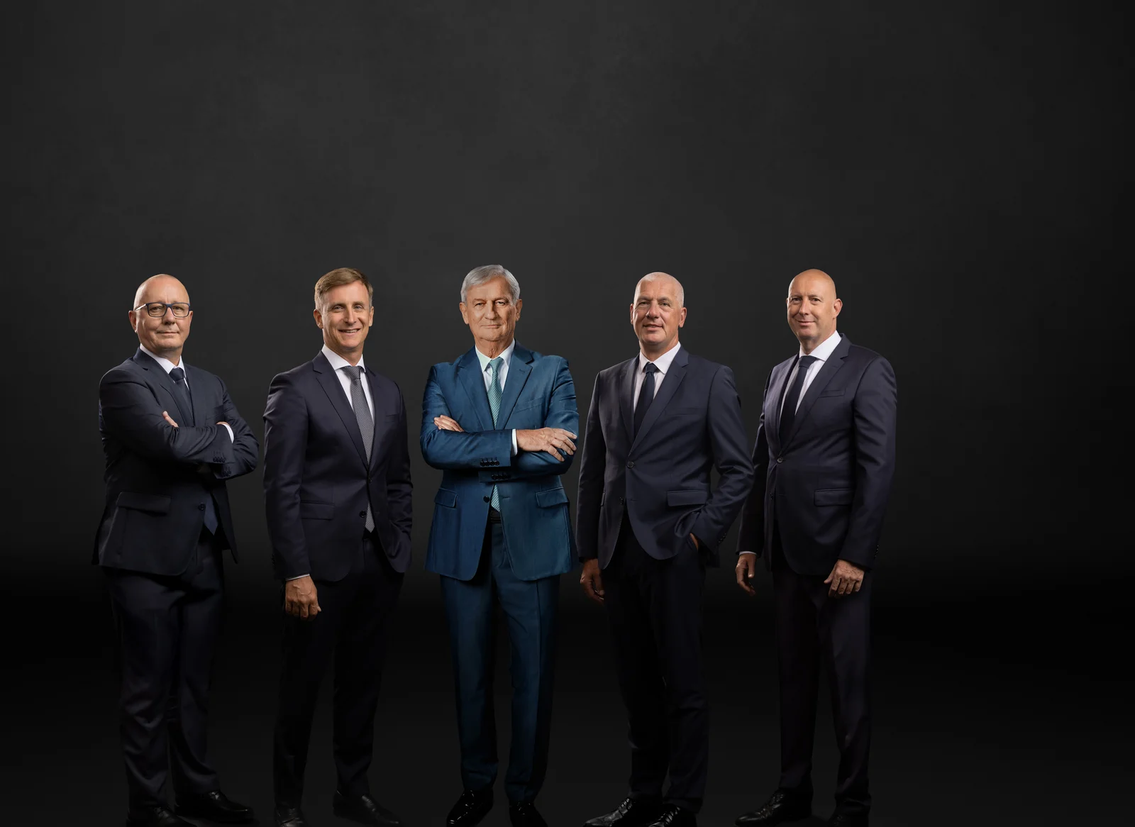 The main management in front of a black background. Six men smile into the camera. 