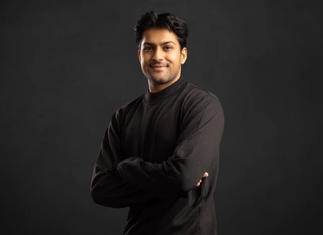 A man smiles into the camera with his arms crossed.