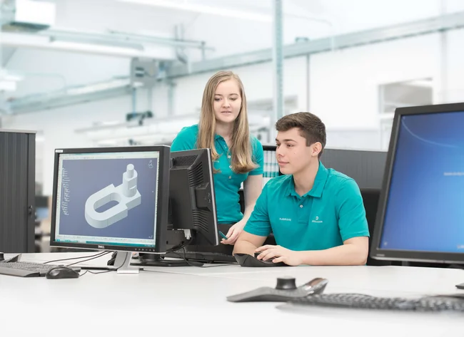 Ein Auszubildender im Produktdesign bei DRÄXLMAIER in Vilsbiburg, der konzentriert an einem Modell am Computer arbeitet.