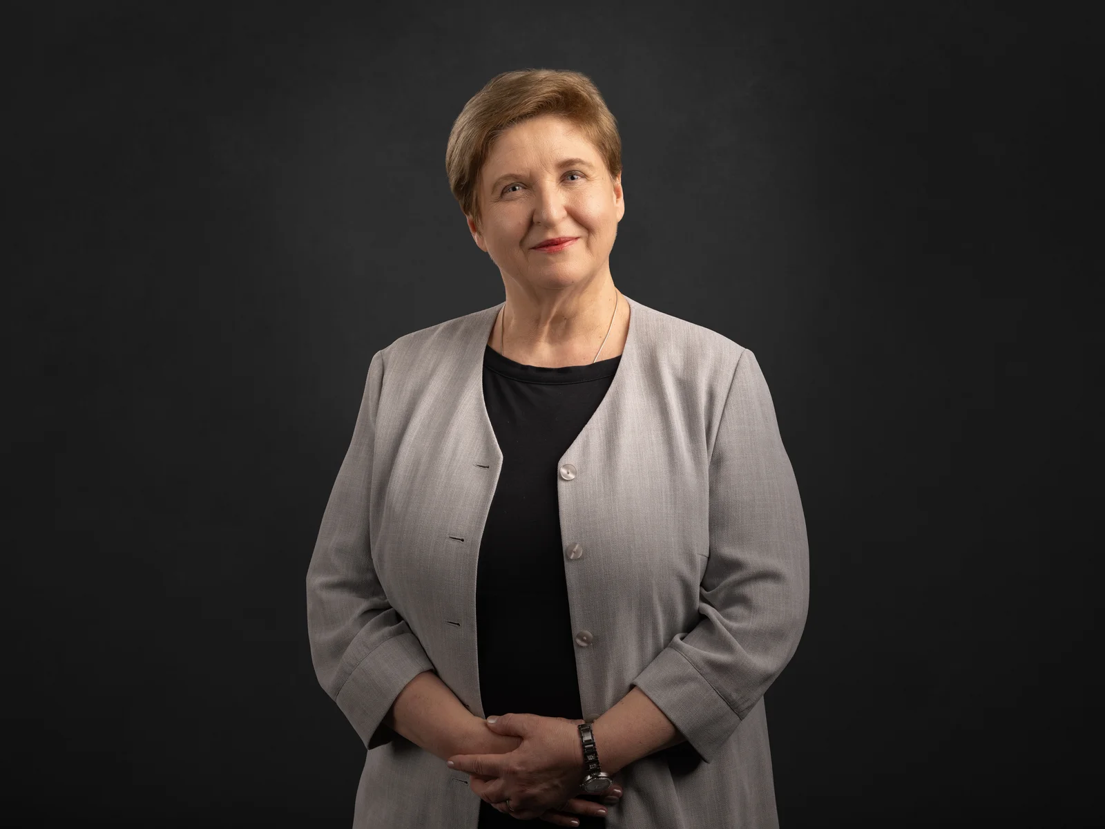 A woman in a grey jacket smiles at the camera.