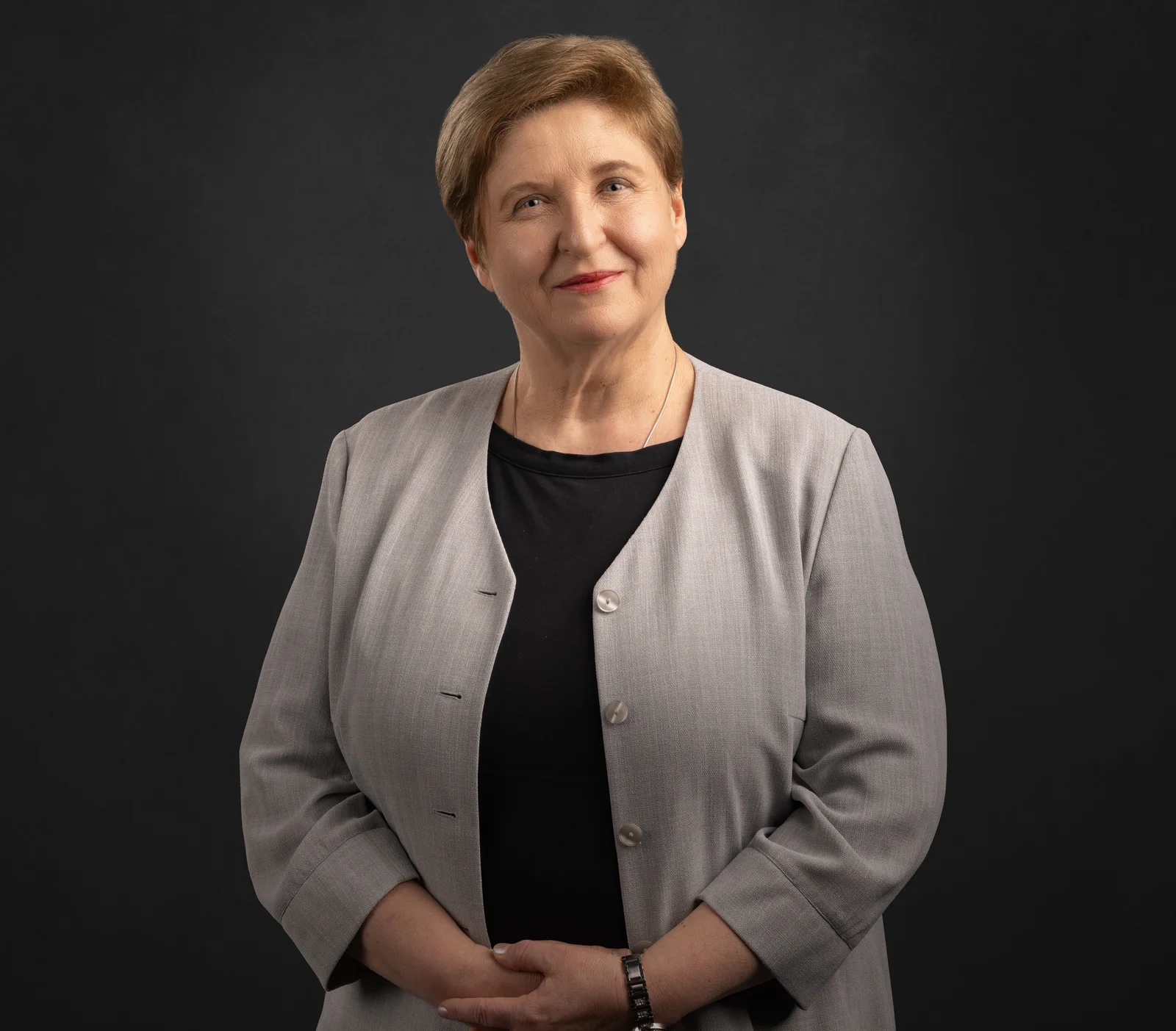 Eine Frau im grauen Jackett lächelt in die Kamera.