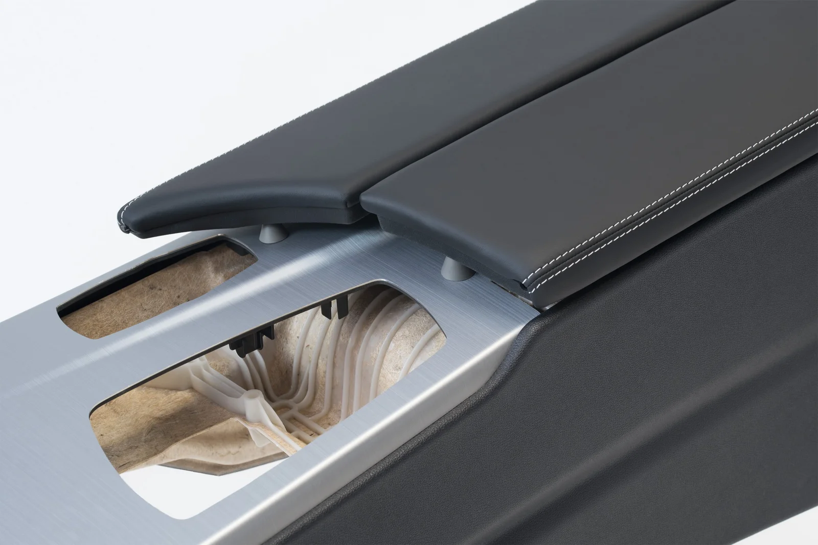 Close-up of a car interior with two black armrests and a silver centre section with cut-outs.