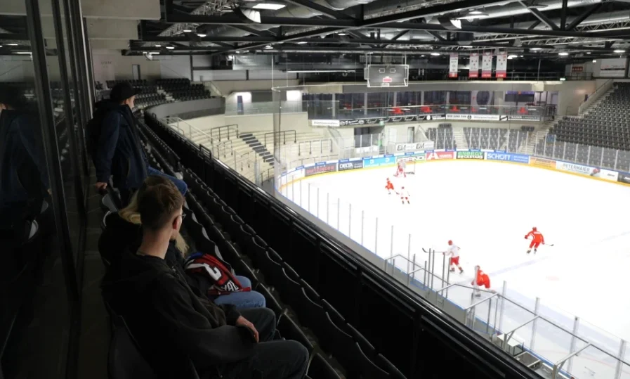 Eishockeyspiel in einer Halle mit Spielern und Zuschauern.