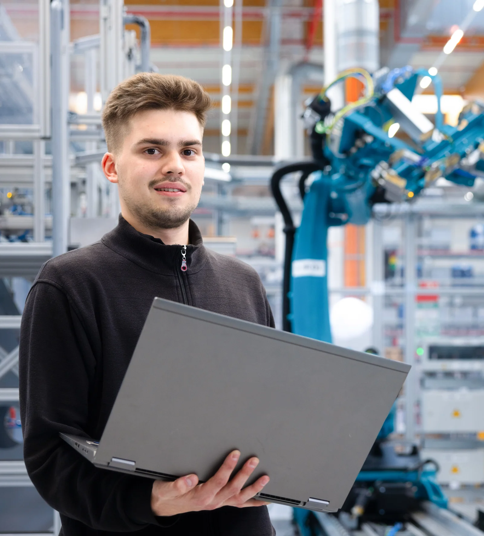 A man in a hall holds a laptop in his hands.