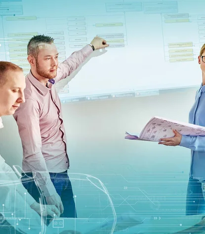 Three employees give a presentation that is projected onto a wall. One employee holds a plan.