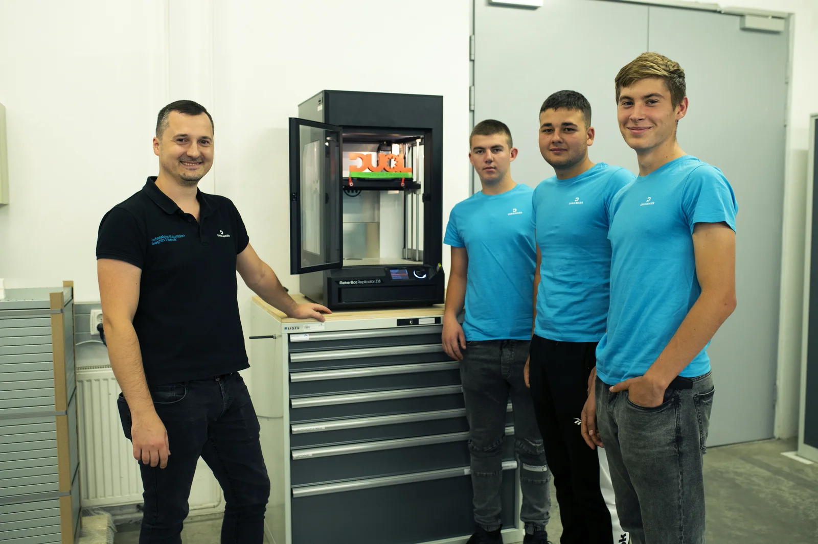 Three trainees and an instructor from Balti stand smiling next to a machine.