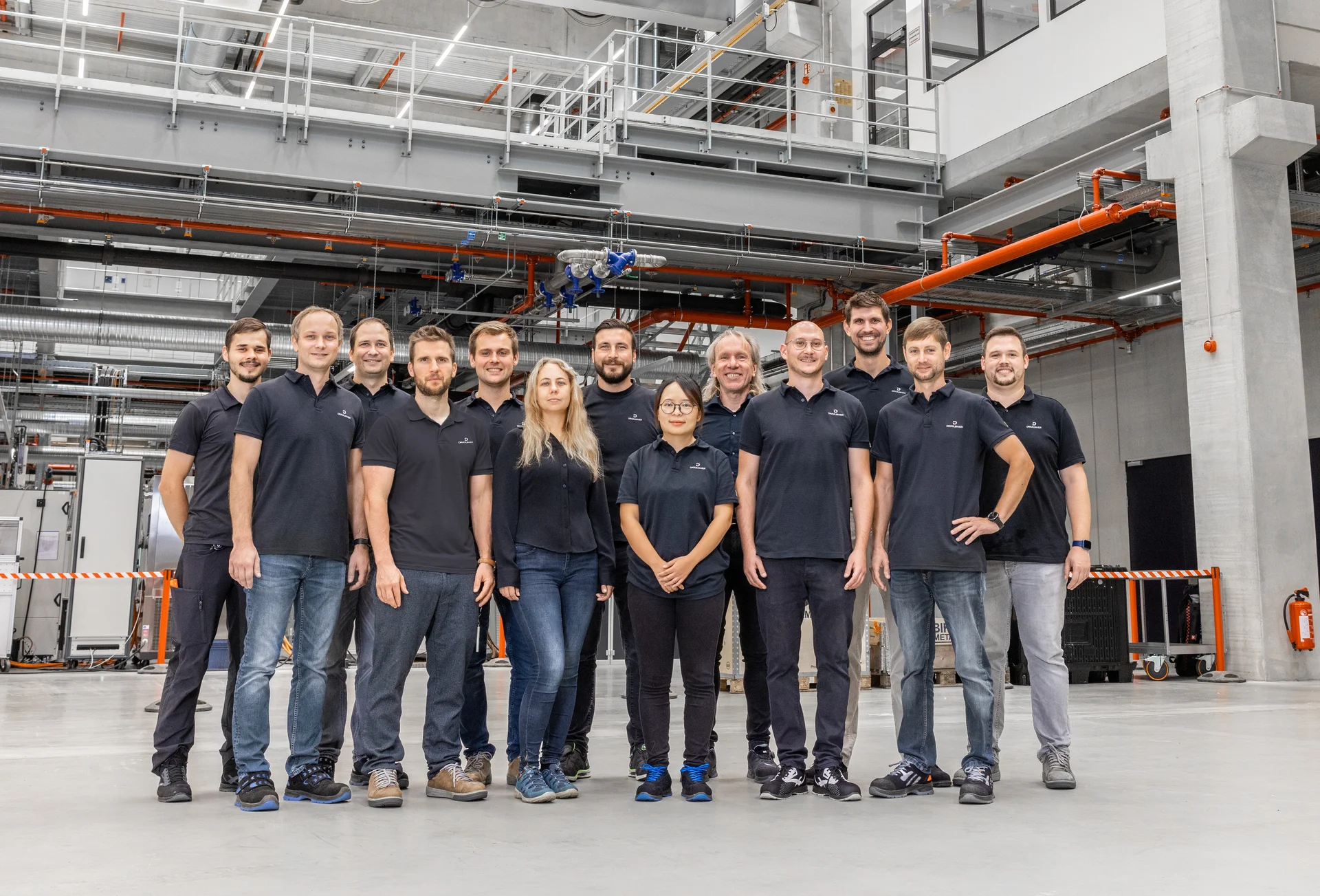 Ein Gruppenfoto mit lächelnden DRÄXLMAIER Produktionsmitarbeitern in einer Halle.
