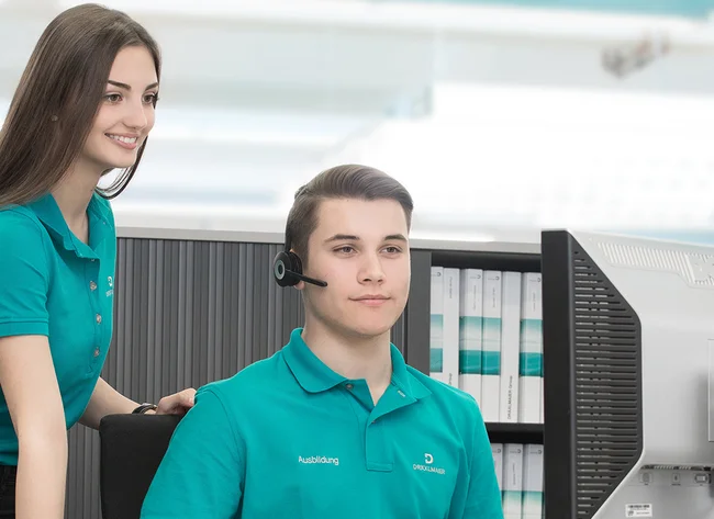 Zwei Auszubildende zu Fremdsprachenindustriekaufleuten betrachten lächelnd einen Bildschirm.