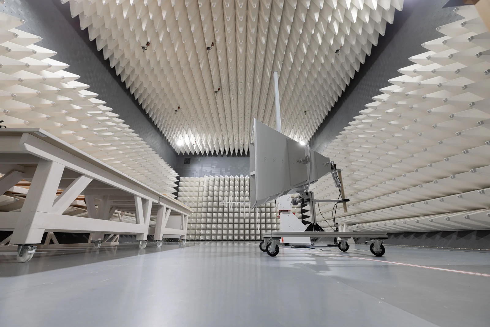 Anechoic chamber with pyramid-shaped foam panels and a mobile device with antenna.