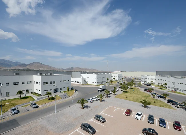A picture of the DRÄXLMAIER buildings in San Luis Potosi. Blue sky and palm trees can be seen. 